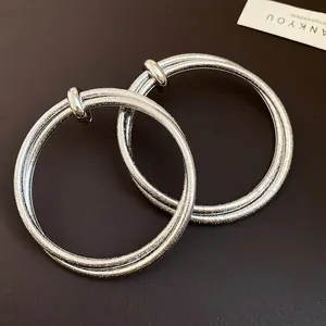 Detailed macro view of silver-toned hoop earrings with unique wrinkled texture.