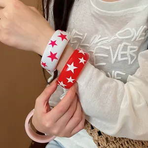 Gros plan de bracelets en résine avec étoiles rouges et blanches au poignet.