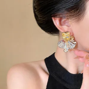 Macro view of French style gold and silver floral stud earrings with tiny diamonds
