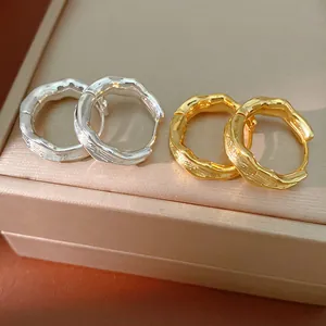 Macro view of textured 18k gold plated and silver hoop earrings on a jewelry box