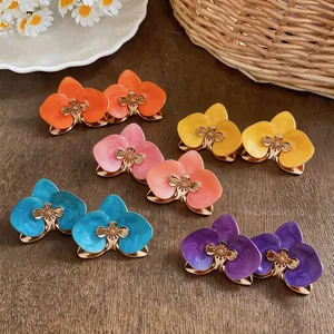 Vielfalt an bunten Emaille-Blumenohrsteckern mit goldenen Retro-Details auf Holzhintergrund