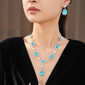 Close-up of elegant blue teardrop crystal necklace and earring jewelry set on model