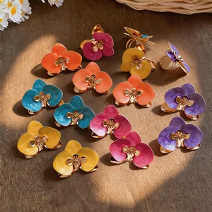 Nahaufnahme bunter Emaille-Orchideenringe auf einer natürlichen Holzoberfläche