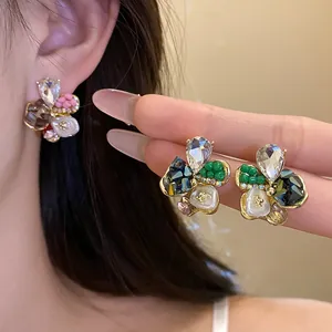 Close-up of elegant flower stud earrings with sparkling rhinestones and colorful beads.