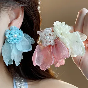 Macro detail of handmade beaded flower earrings with soft chiffon petals and pearl