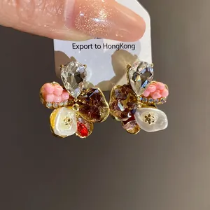 Close-up detail of floral stud earrings featuring crystals, beads and pearl accents