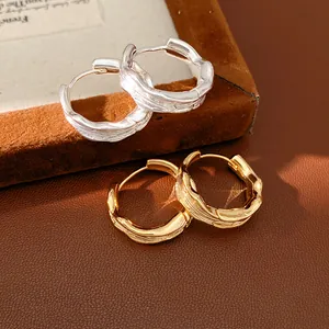 Detailed close-up showing the unique wrinkled texture of 18k gold and silver hoop earrings.