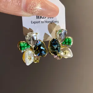 Close-up of elegant floral stud earrings with green beads and pearls