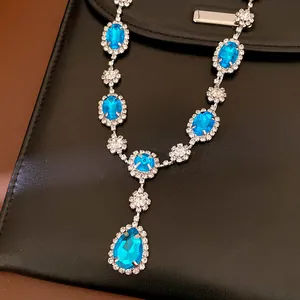 Close-up of elegant royal style necklace with blue teardrop and oval gems and rhinestones.