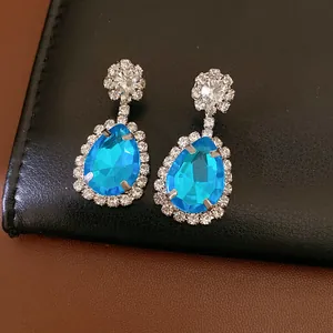 Elegant light blue teardrop dangle earrings with clear rhinestone halo set on black leather