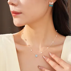 Elegant beaded pearl necklace set with a blue zircon pendant worn by an Asian model