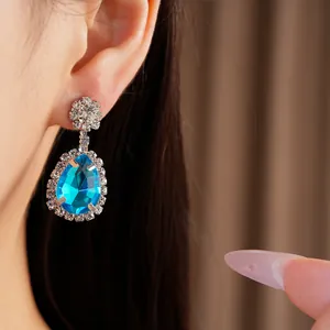 Detailed view of elegant water drop earrings featuring a vibrant blue gemstone.