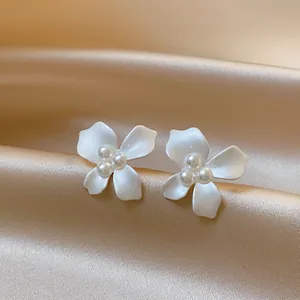 Detailed macro view of elegant white flower stud earrings with pearl centers on satin