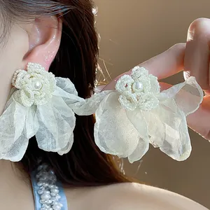 Close-up of elegant chiffon flower earrings with pearl centers on an Asian model's ear
