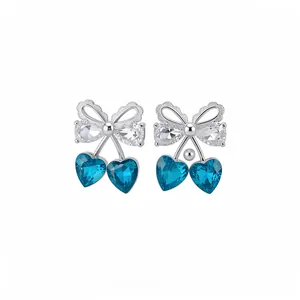 Elegant silver bow earrings with teardrop zircons and blue heart crystals on white background.
