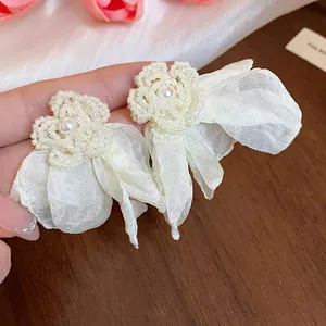 Close-up of elegant chiffon flower earrings with central pearl and bead detailing