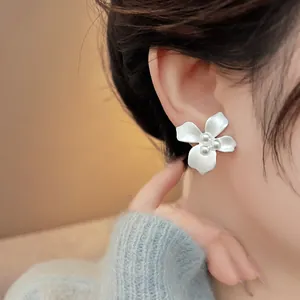Close-up of white flower stud earrings with pearl centers on model
