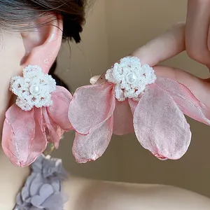 Close-up of elegant pink chiffon flower pearl earrings with delicate beadwork and texture