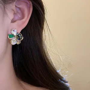 Close-up view of an elegant flower stud earring with pearls and crystals worn on the ear.