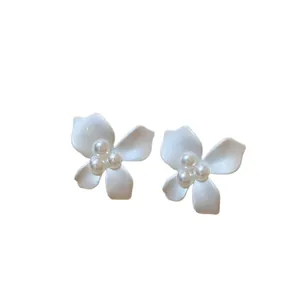 Elegant white flower stud earrings with clustered cream pearls on plain background