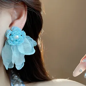 Close-up of elegant blue chiffon flower earrings with pearl and beadwork detail