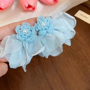 Close-up detail of blue chiffon flower earrings with delicate pearl and bead accents
