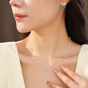 Detailed view of a light blue zircon and pearl necklace worn by an elegant female model