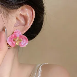 Detailaufnahme eleganter rosa Orchideen-Ohrstecker mit goldenem Vintage-Metallzentrum