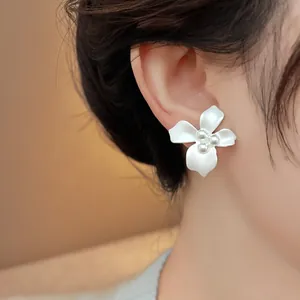 Close-up of elegant white flower stud earrings with pearl centers on model