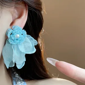 Detailed macro shot of elegant blue beaded flower earrings with chiffon petals and pearl center