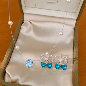 Detailed shot of blue crystal flower pendant and bow heart earrings set in gift box