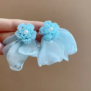 Close-up of light blue beaded flower earrings with chiffon petals and pearl