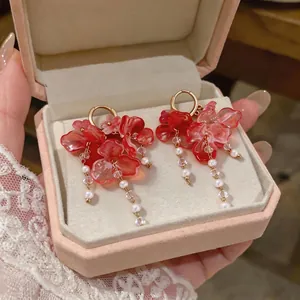 Exquisitos pendientes de aro con flores rosas y borlas de perlas en un joyero rosa