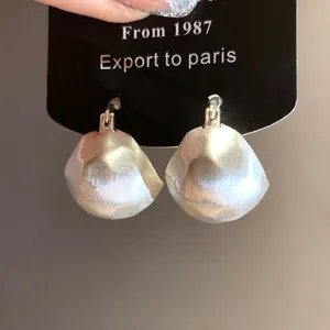 Macro view of brushed silver semi-circular earrings with retro metallic texture and finish