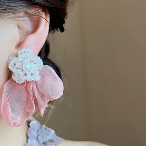Close-up detail of elegant pink chiffon flower stud earrings with pearl and white bead center