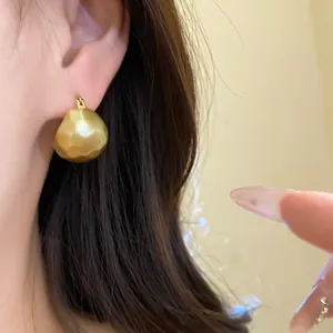 Detailed view of elegant golden brushed semi-circular hoop earring worn on a female ear