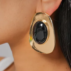 Detailed view of vintage chunky gold metallic earrings featuring a black oval resin stone.