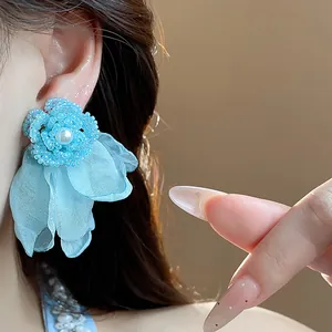 Detailed macro view of a light blue chiffon flower earring featuring a central pearl