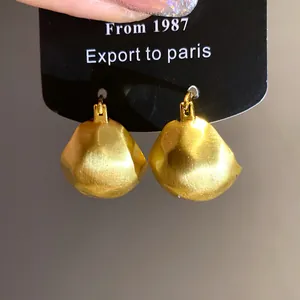 Close-up of vintage gold brushed semi-circular dome earrings featuring a matte finish
