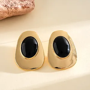 Close-up of vintage style gold-toned geometric oval earrings with a polished black resin inlay