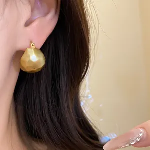 Macro shot of a textured gold semi-circle earring on model, showing matte finish details.