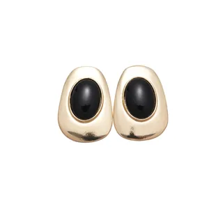 Vintage gold metal oval stud earrings with black resin inlay on white background