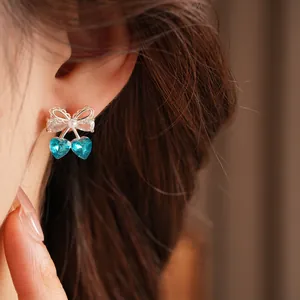 Close-up of elegant bow earrings with blue heart-shaped crystal drops