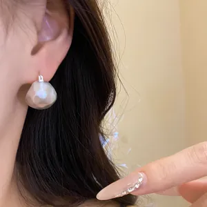 Detail view of a minimalist brushed silver semi-circular hoop earring worn on ear