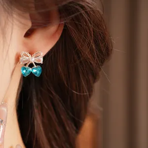 Close-up of elegant blue heart crystal earrings with zircon bow and pearl detail