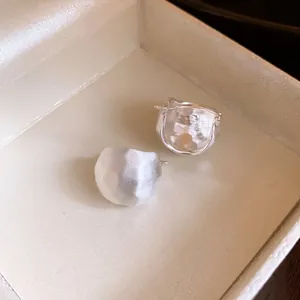 Close-up of minimalist brushed silver semi-circle earrings in gift box