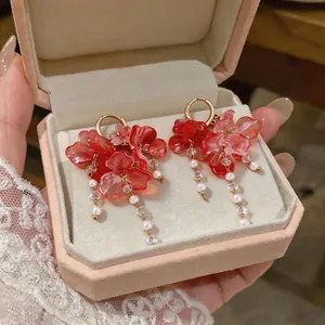 Primer plano de pendientes de borla con flores rosas en un joyero de regalo rosa