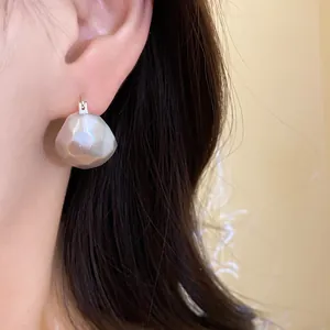 Detailed close-up showing elegant brushed silver semi-circular earrings worn on a model's ear