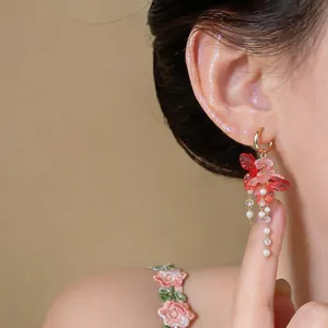 Detalle macro de elegantes pendientes de borlas con flores rosas y perlas en modelo