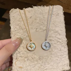 Dettaglio di collane con pendente stella e luna placcate oro 14k su carta testurizzata